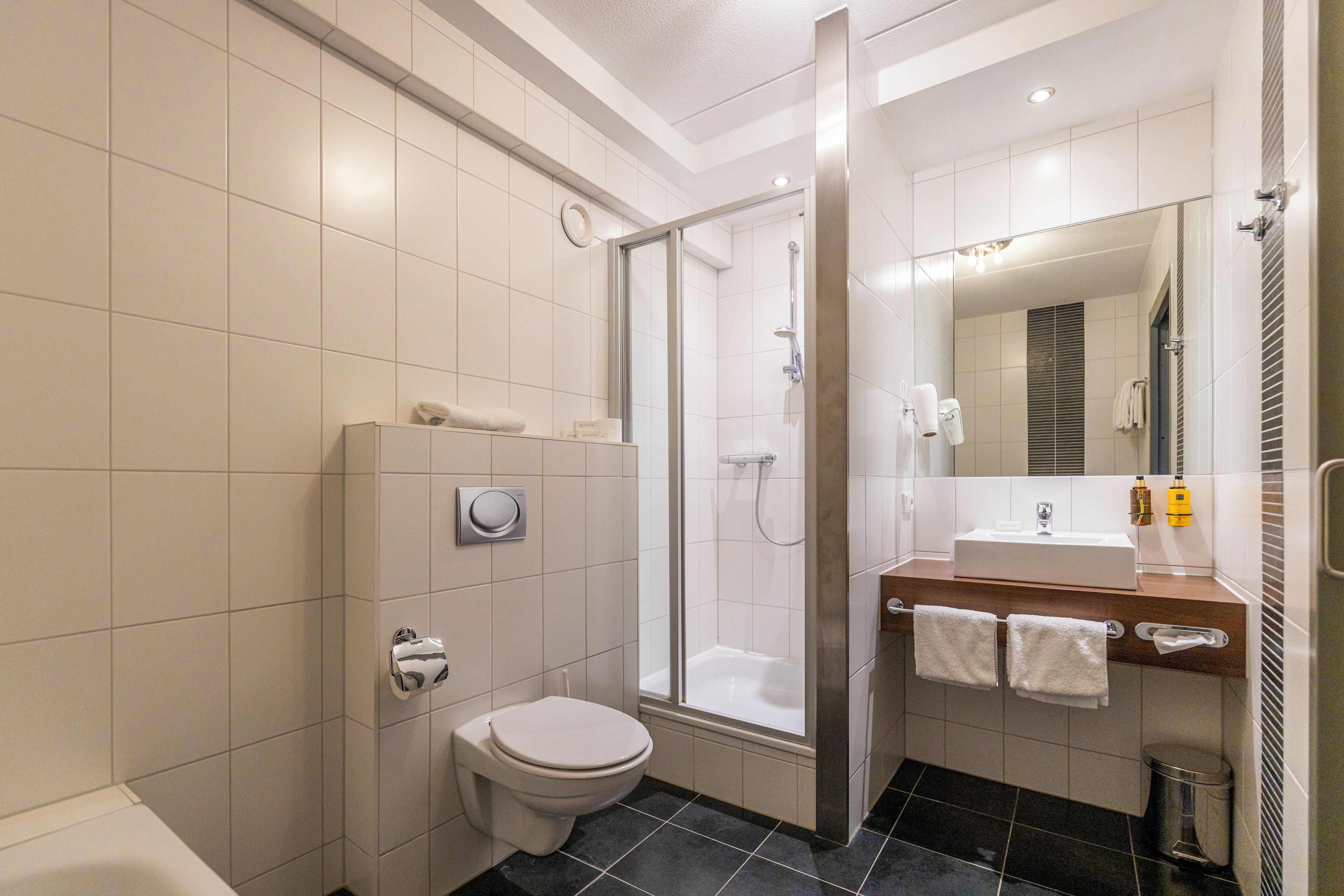 A modern bathroom with a toilet, shower, and sink.
