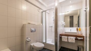 Een moderne badkamer met toilet, douche en wastafel.