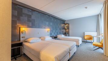 Een hotelkamer met twee bedden, een klein tafeltje, een stoel en een wandplank met een vaas.
