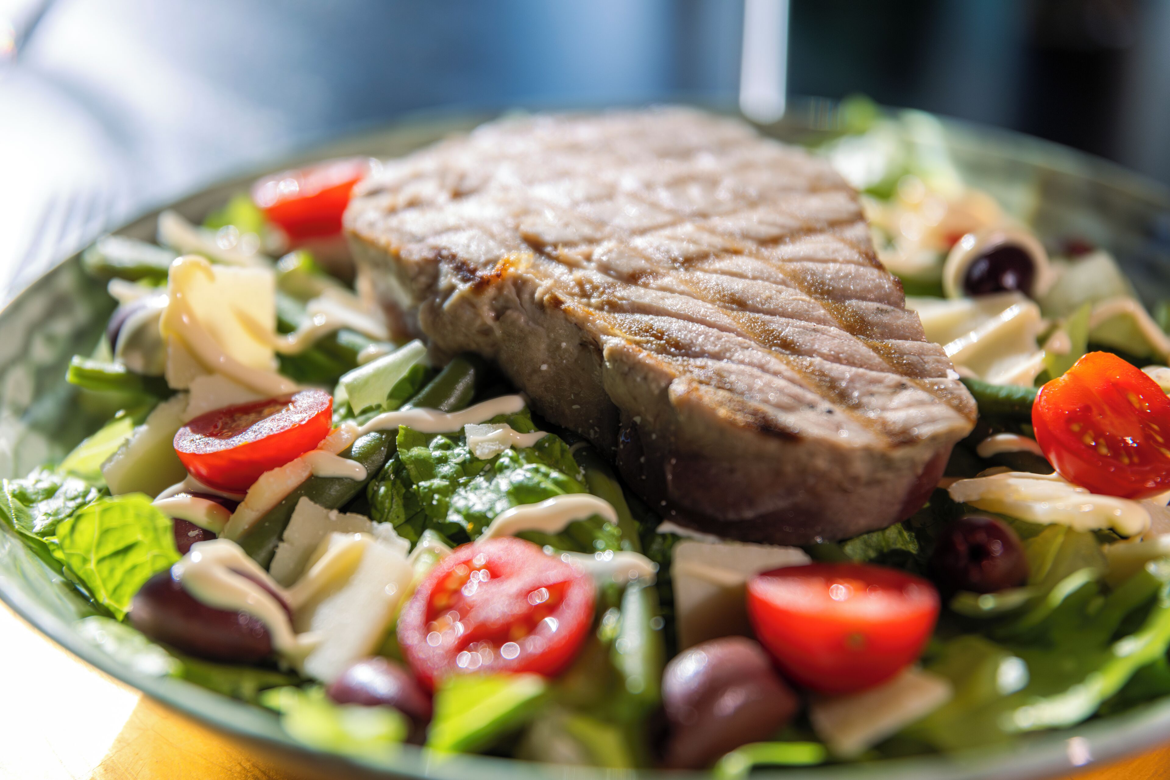 A plate of food with a grilled steak, salad, and cherry tomatoes.