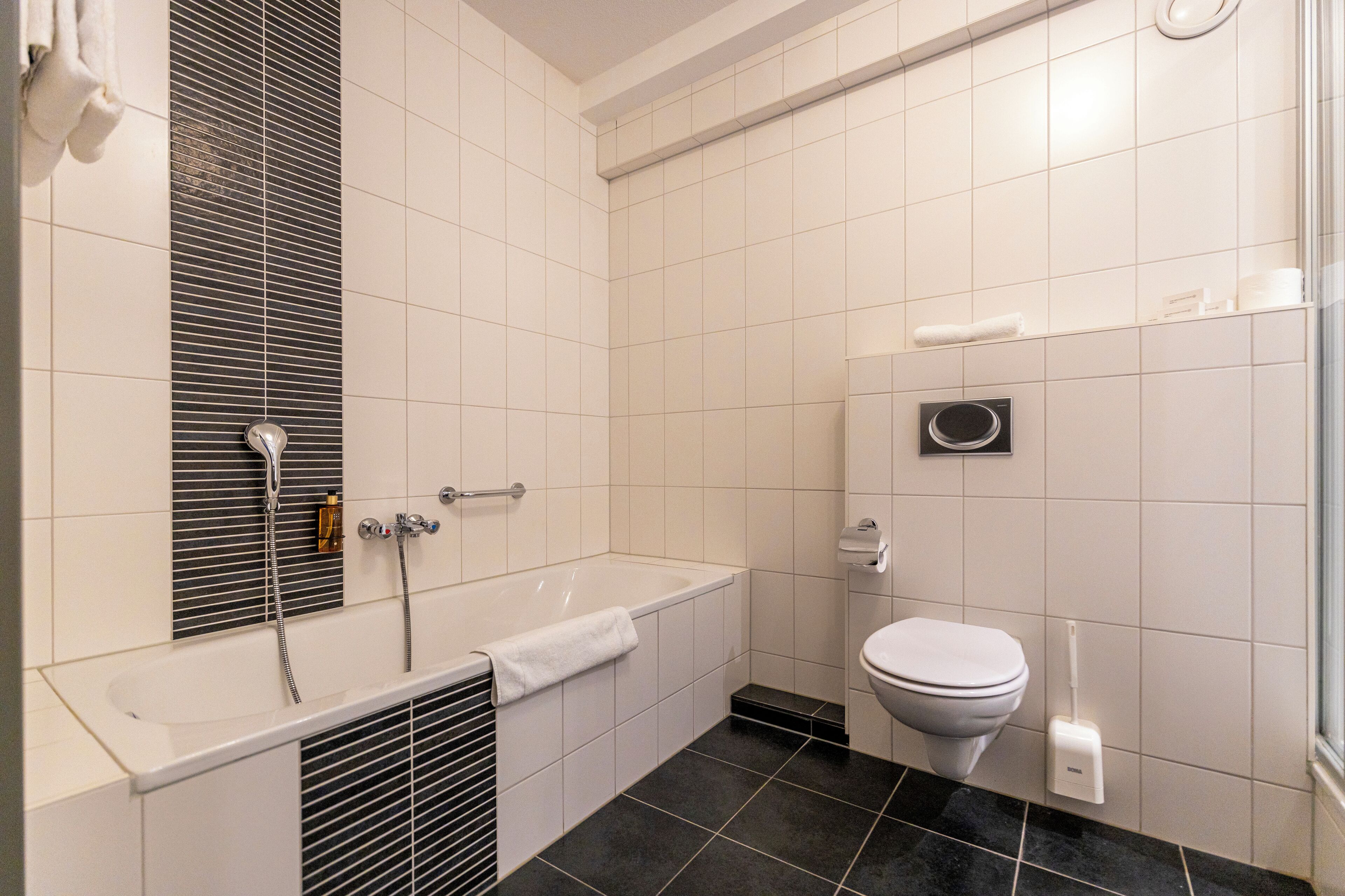 Un bagno moderno con vasca, servizi igienici e un grande specchio.
