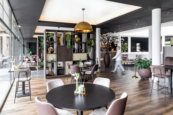 A modern interior with round tables, chairs, and a variety of plants.