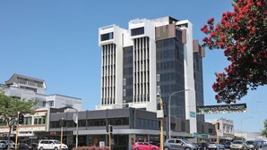A modern building with a glass facade and a sign that reads "HAPPY HOLIDAYS, PALSMY!" - Ramada Encore By Wyndham Palmerston North (Palmerston North)