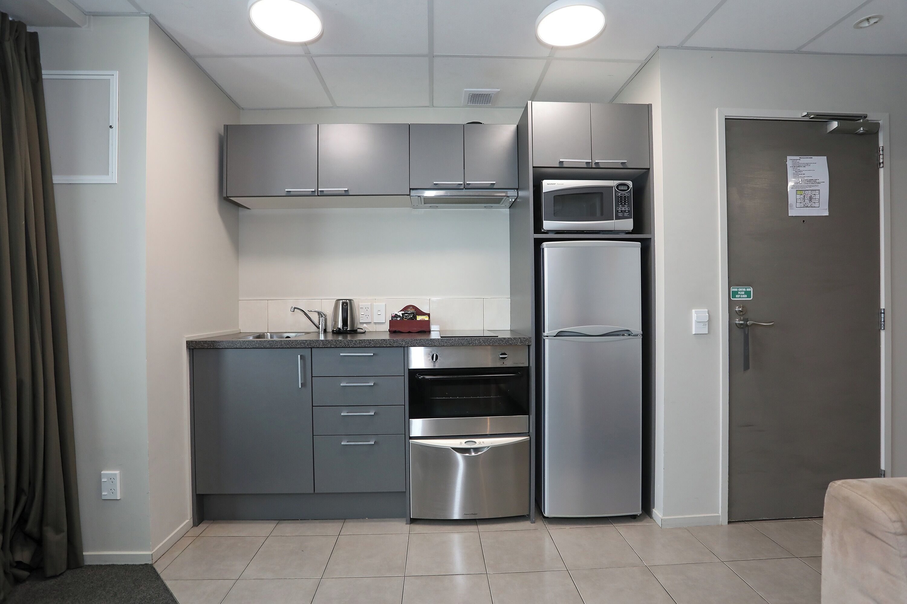 A compact kitchen with a microwave, oven, and refrigerator.
