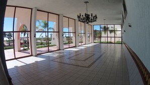 A spacious corridor with large windows, a tiled floor, and a chandelier. - Hotel Mision Santa Maria (San Quintin)