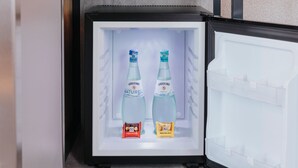 A refrigerator with two bottles of Gerolsteiner Naturell water and two snack packets. - Premier Inn Köln City Mediapark (Cologne)