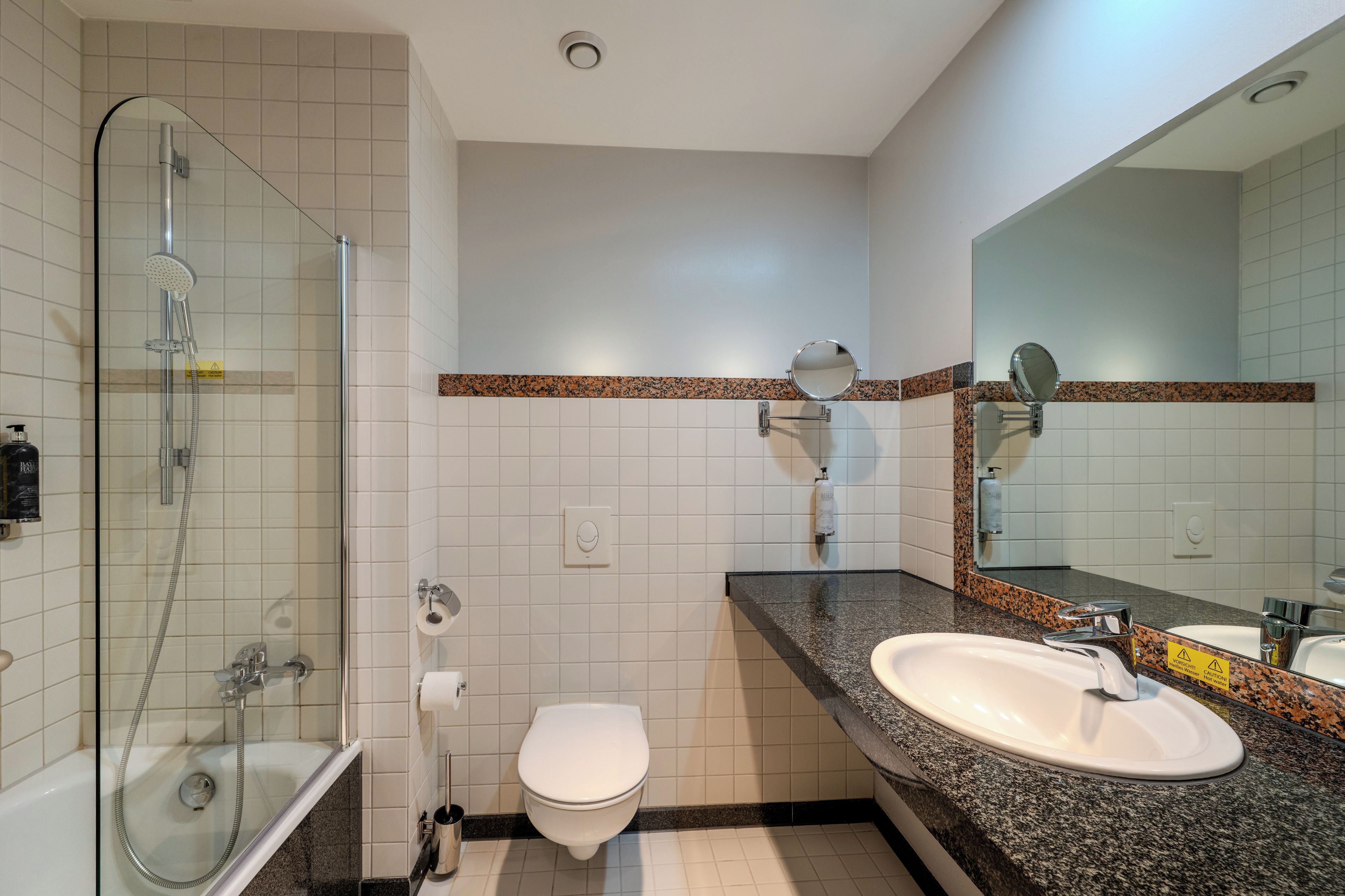 Une salle de bain avec une douche à parois de verre, des toilettes, un lavabo avec un miroir et un porte-serviettes.