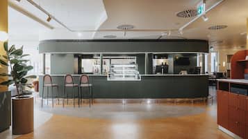 Un bar moderno con mostrador, asientos y una planta grande en maceta.