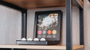 A framed Roombar menu with coffee options and a coffee machine below it. - Premier Inn Köln City Mediapark (Cologne)