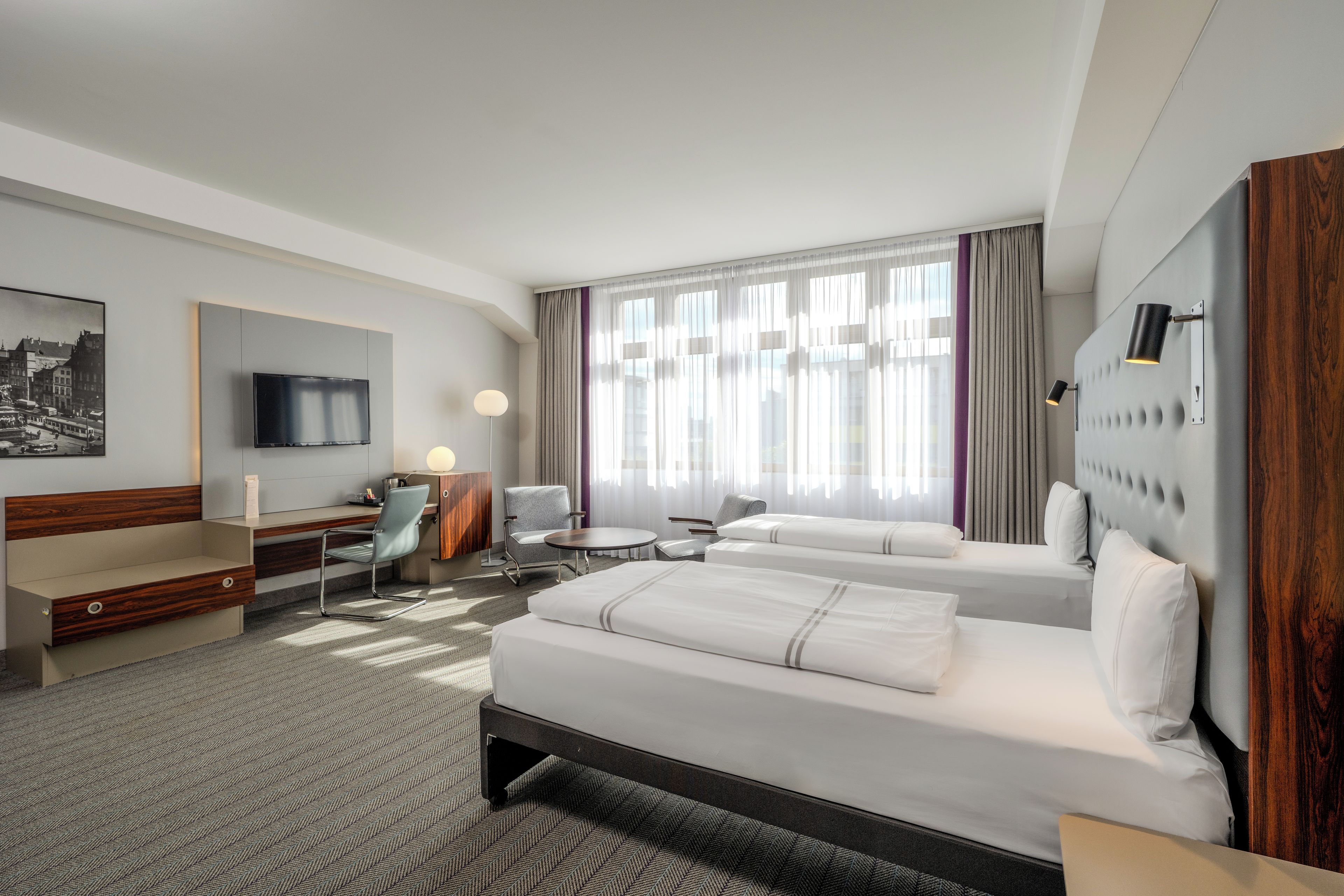 Una habitación de hotel con cama, escritorio, silla y televisor.