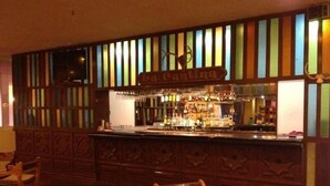 Una zona de bar con mostrador de madera, un letrero que dice "La Cantina" y un espacio de asientos con sillas de madera.