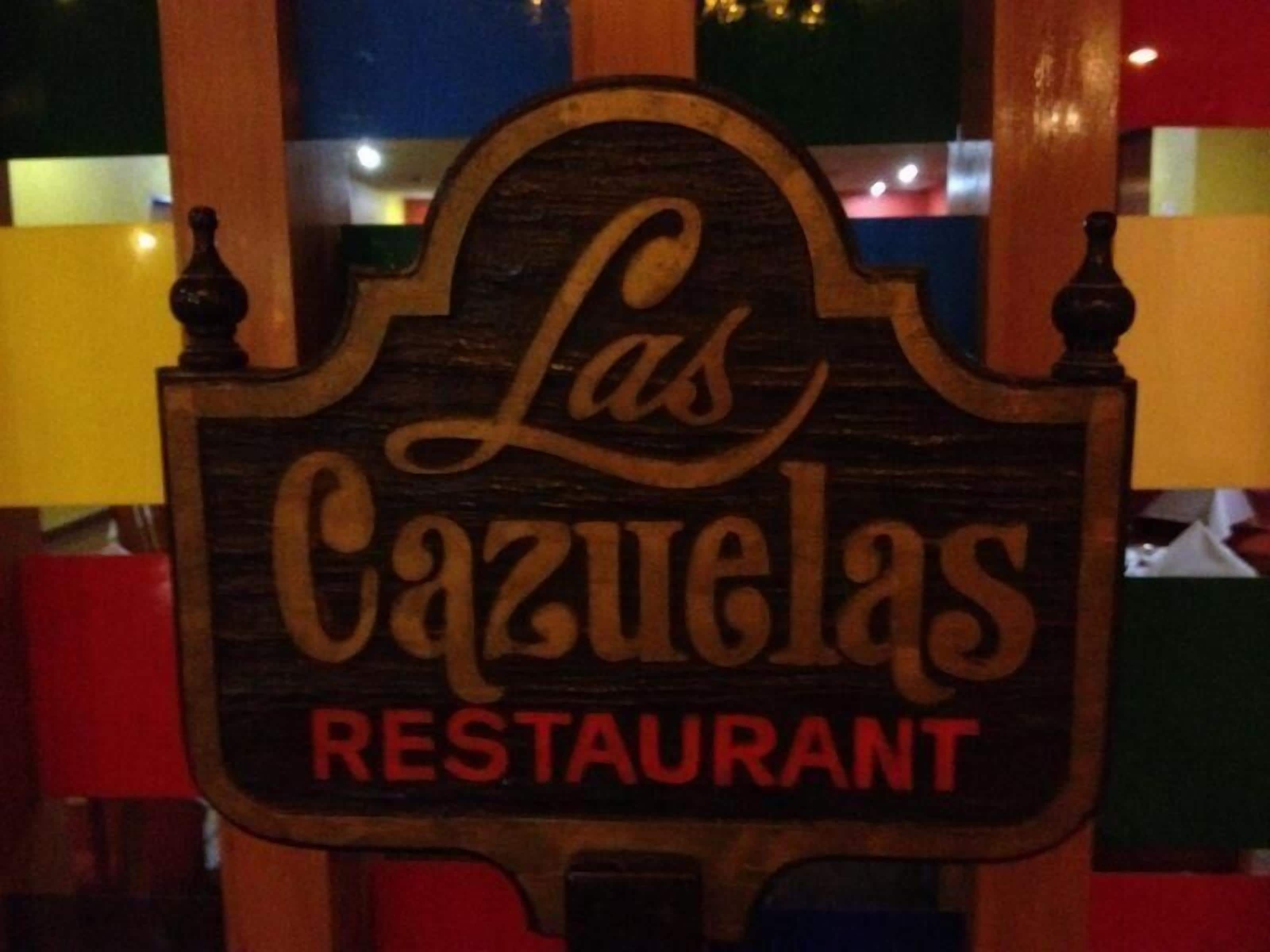 Un cartello in legno per 'Las Cazuelas Restaurant', con un design semplice e rustico.