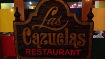 Un cartello in legno per 'Las Cazuelas Restaurant', con un design semplice e rustico.