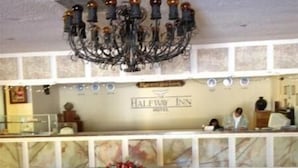 Zona de recepción con candelabro, mostrador de recepción y cartel del Hotel Halfway Inn.
