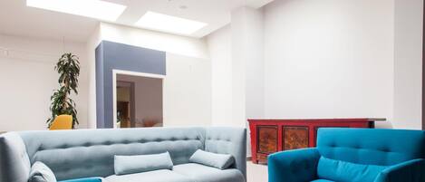 A modern living room with a light grey sofa, a blue armchair, and a red cabinet.