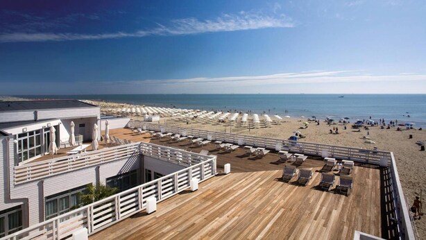 A beachside hotel deck with sun loungers and umbrellas, overlooking a sandy beach and the ocean. - Terme Beach Resort (Ravenna)