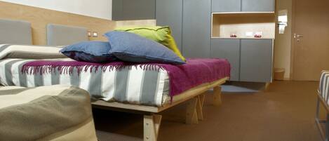 A modern bedroom with a bed, a small desk, and a wardrobe.