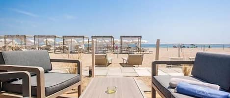 Een privéstrand, ligstoelen aan het strand, parasols, een strandbar