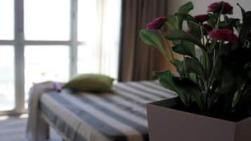 Un dormitorio con cama, ventana y planta en maceta con flores.
