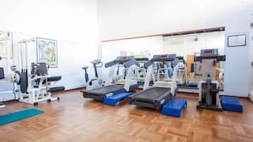 A gym with treadmills, weight machines, and a mirror wall.