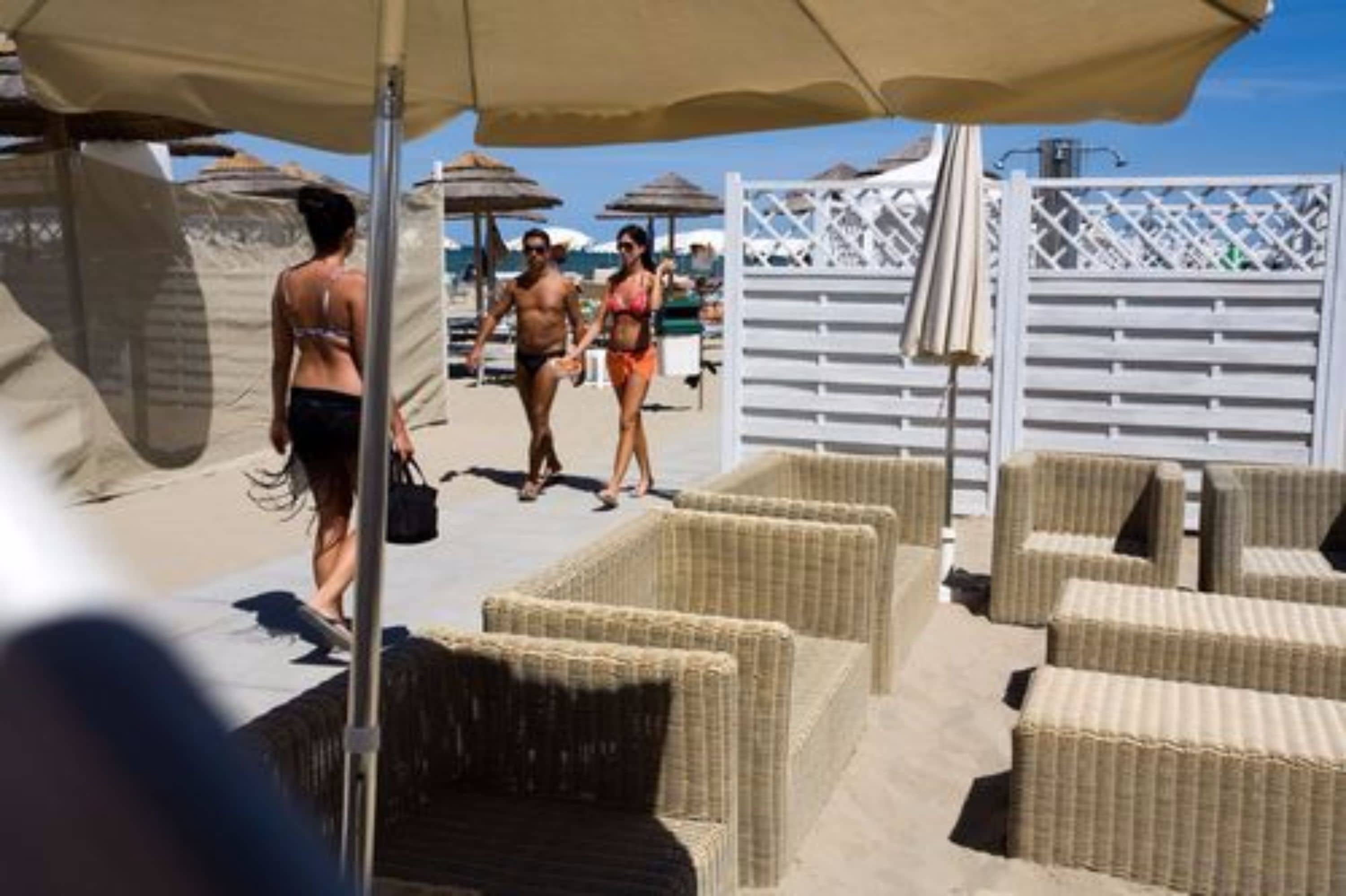 A beachside area with wicker lounge chairs and umbrellas.