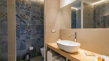 Un baño moderno con un espejo grande, un lavabo sobre encimera y baldosas con motivos en las paredes.