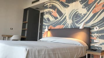 Camera d'albergo con un letto, un comodino, una lampada e una parete con decoro a motivo di onda.