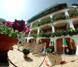 A courtyard with a multi-level building, potted plants, and outdoor seating areas. - Il Gabbiano (Positano)