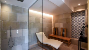 Relax in a serene bathroom with a glass-enclosed shower, cushioned bench, and wooden bench for seating.