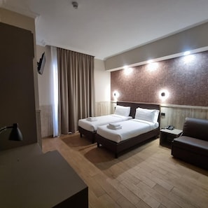 A hotel room with two beds, a desk, a chair, and a patterned wall. - Hotel Pyramid (Rome)