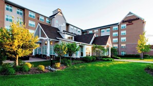 Um hotel moderno com fachada de tijolos, várias janelas e um gramado bem cuidado.