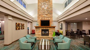 Um hall com lareira de pedra, área de estar e uma tela de televisão.