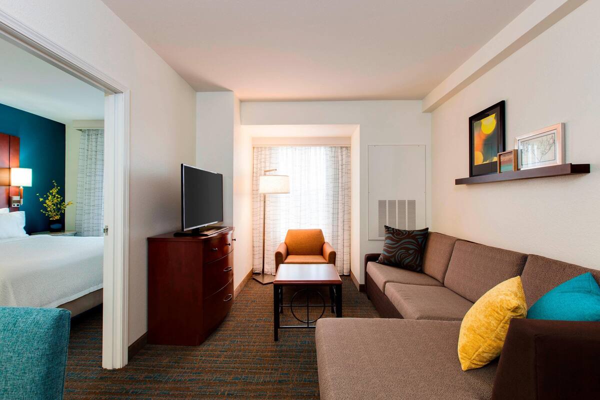 A hotel room with a bed, a sofa, a TV, a desk, and a chair.