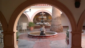 A courtyard with a central fountain, surrounded by arches and potted plants. - Hotel Mision Catavina (Catavina)