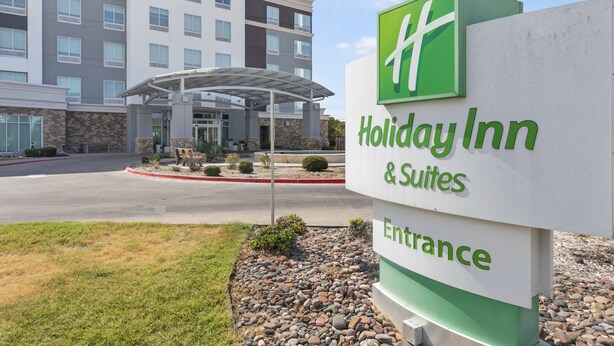 Señal de entrada de Holiday Inn & Suites, con una vista clara del exterior del edificio.