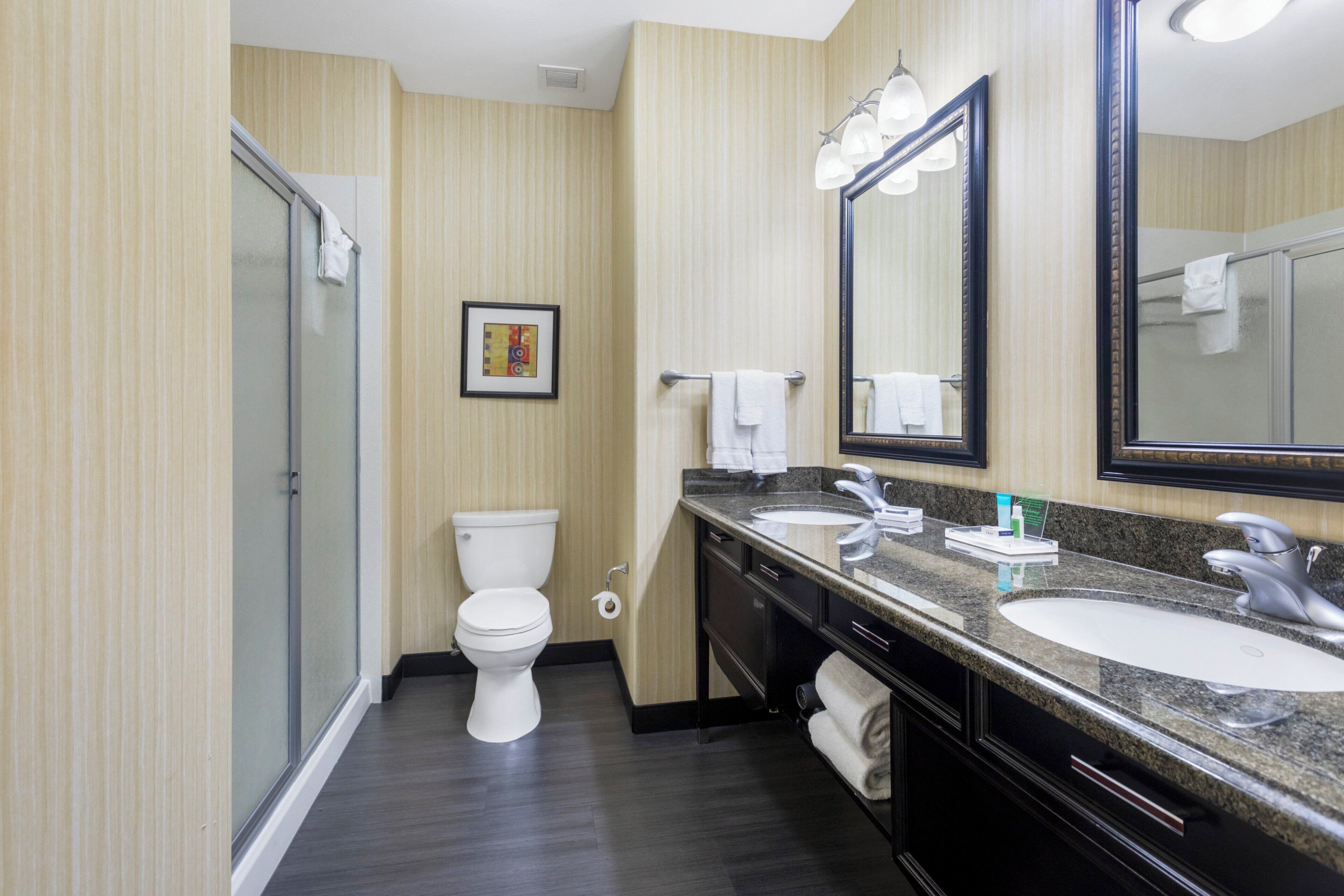 Une salle de bain d’hôtel équipée de toilettes, d’un lavabo, d’un miroir et d’une douche.