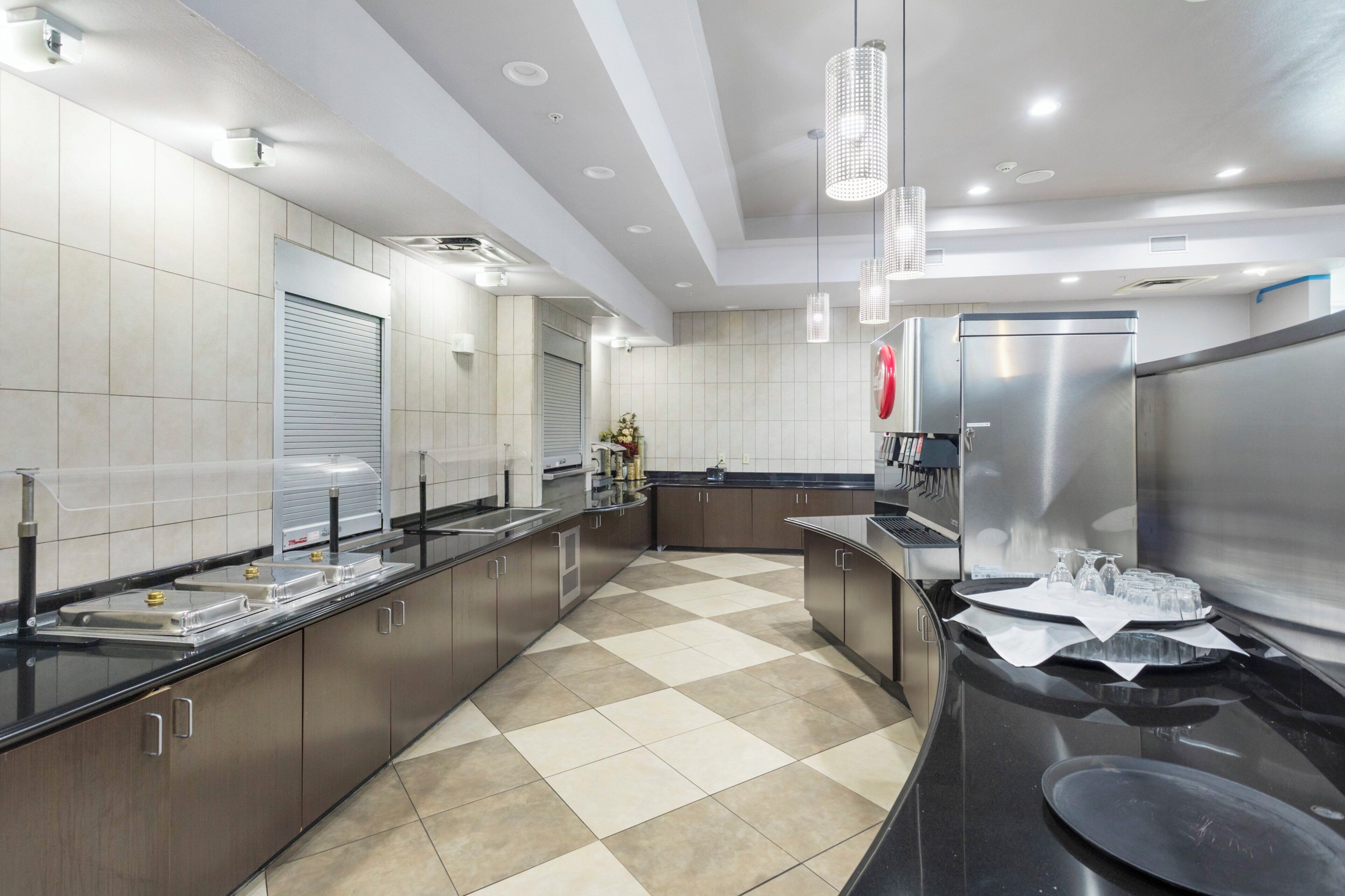 Una cucina moderna con elettrodomestici in acciaio inossidabile, pavimento a scacchi e luci a sospensione.