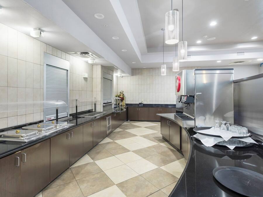 A modern kitchen with stainless steel appliances, a checkered floor, and pendant lighting.