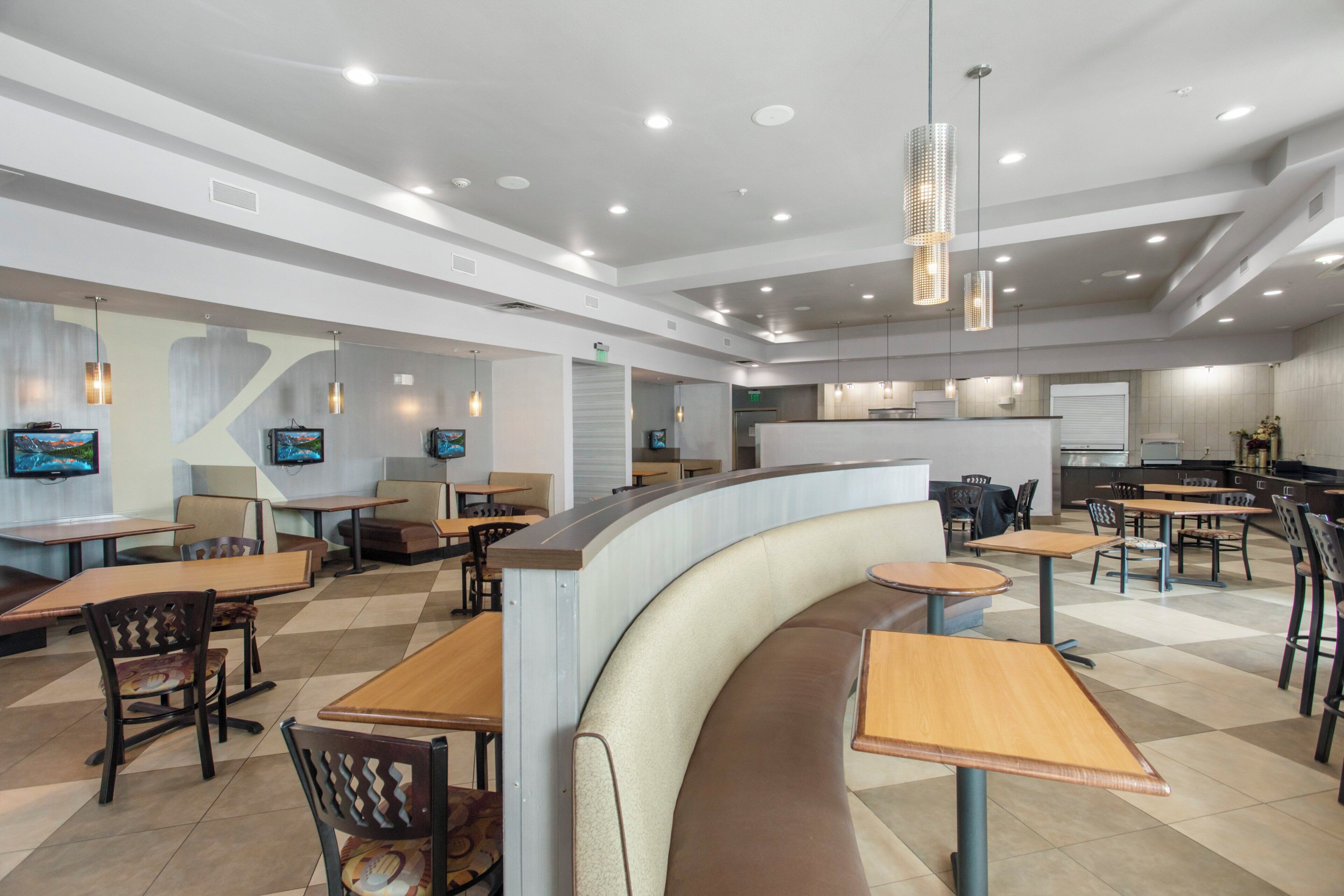 A modern restaurant with a curved counter, multiple seating areas, and recessed ceiling lighting.