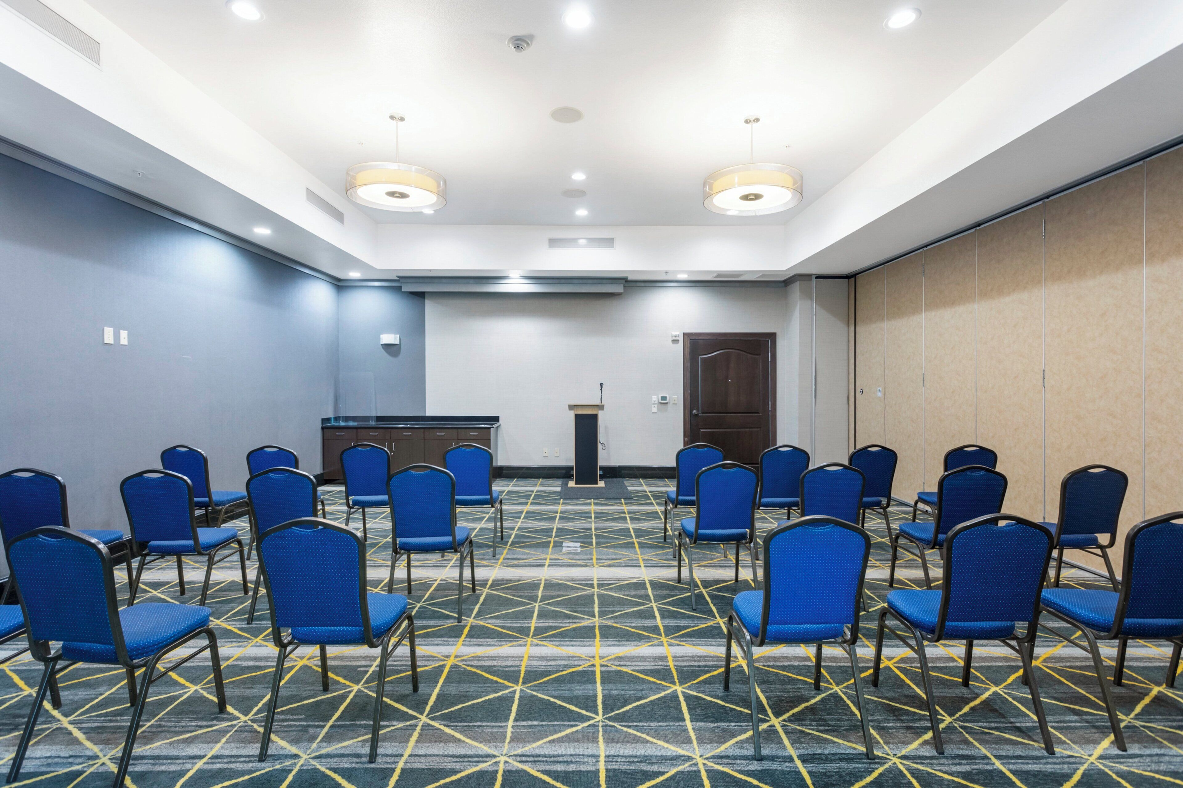 A conference room with rows of chairs, a podium, and a door.