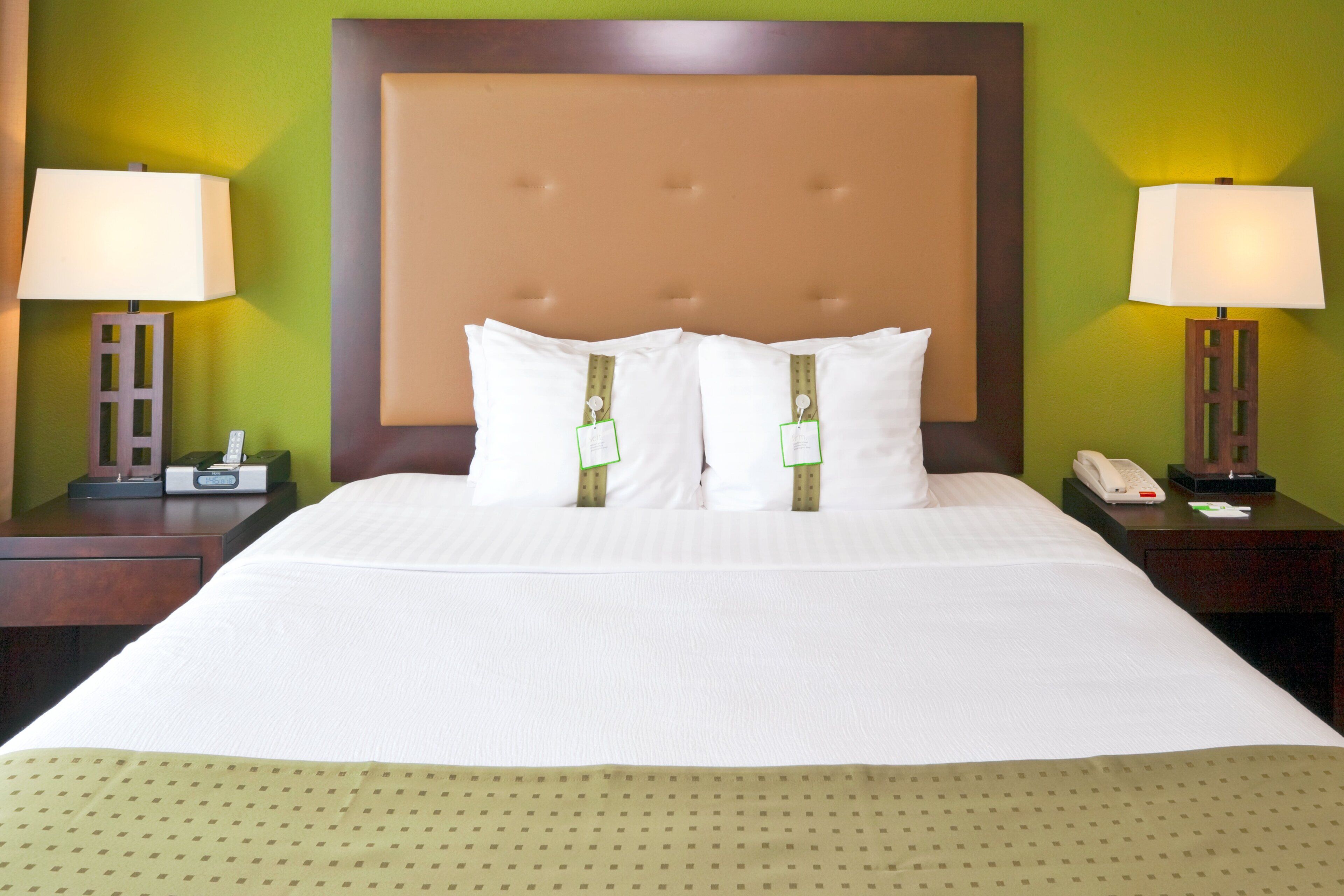 Habitación de hotel con una cama grande, dos mesitas de noche, un teléfono y una lámpara a cada lado.