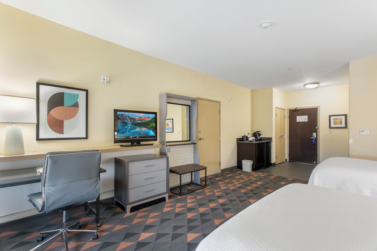 A hotel room with a bed, desk, chair, and a television.