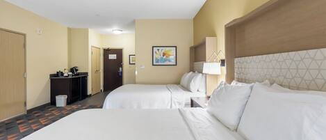 A hotel room with two beds, a desk, a small kitchenette, and a bathroom.