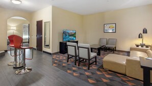 Habitación de hotel con televisión, zona de estar y alfombra estampada.