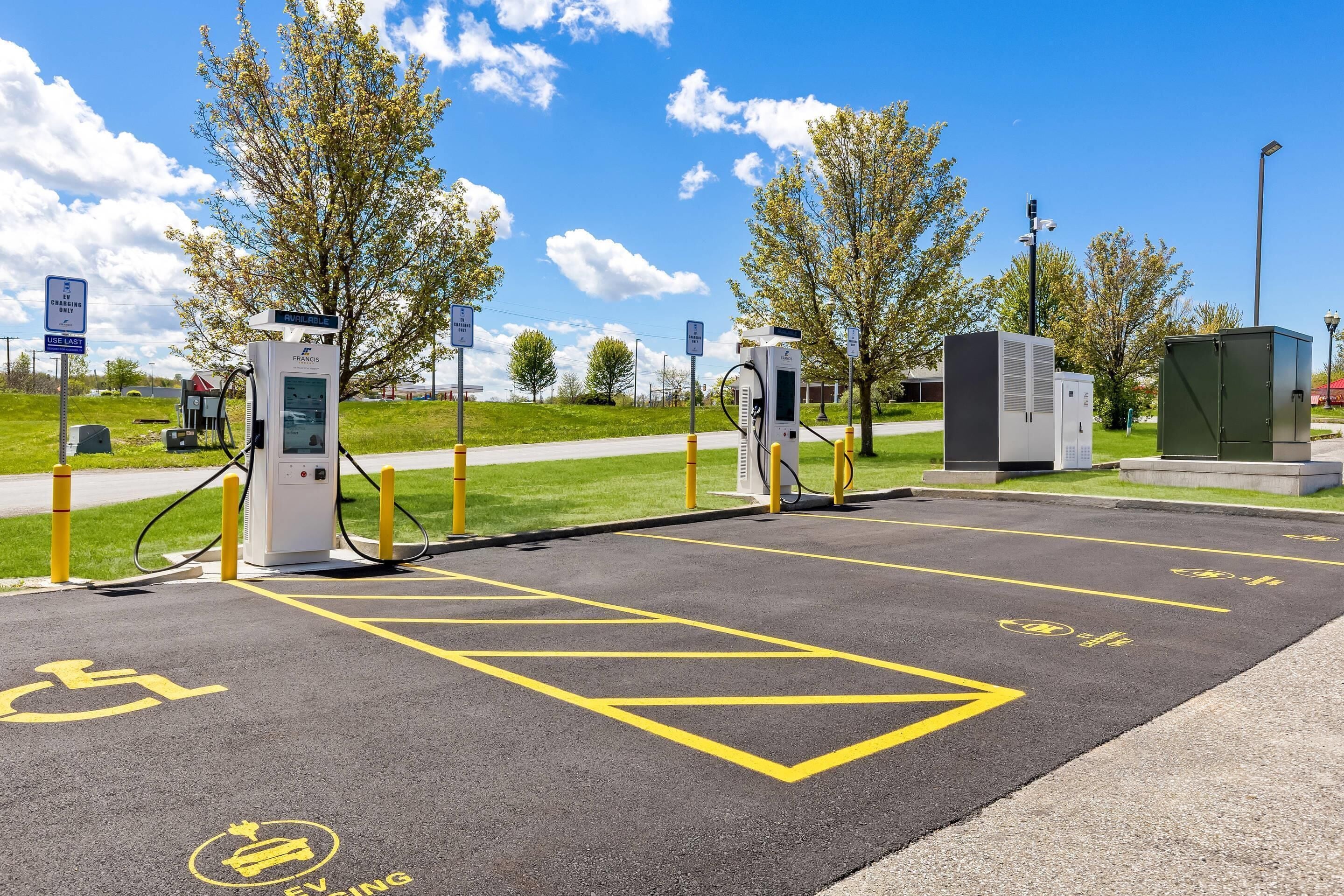 An electric vehicle charging station with a clear path, a wheelchair-accessible area, and a parking lot.
