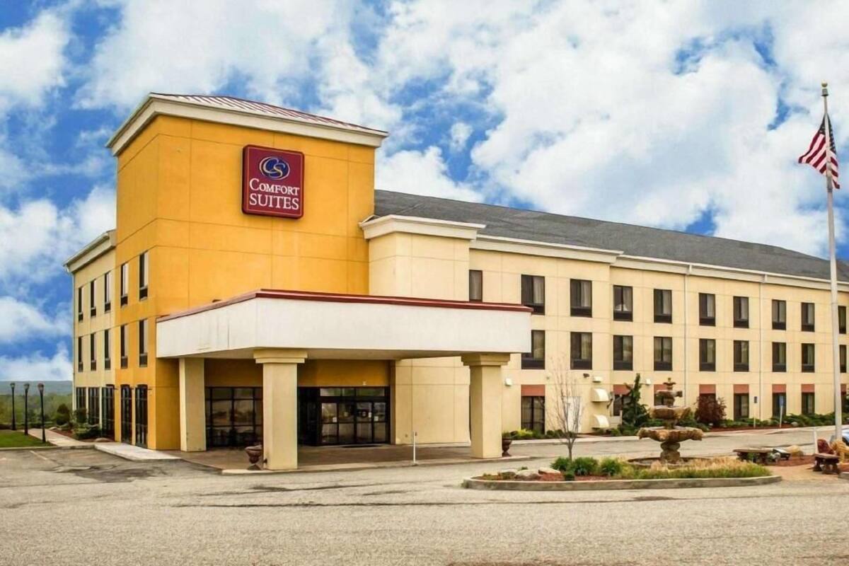 A hotel with a sign reading 'Comfort Suites,' a flag, and a fountain in the courtyard.