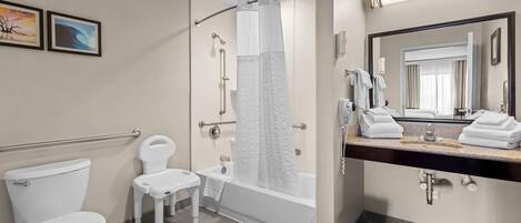 A modern bathroom with a toilet, a shower with a glass door, a vanity with a mirror, and two framed pictures on the wall.