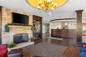 A lobby with a stone fireplace, a flat-screen TV, a reception desk, and a chandelier. - Comfort Suites Edinboro (Edinboro)