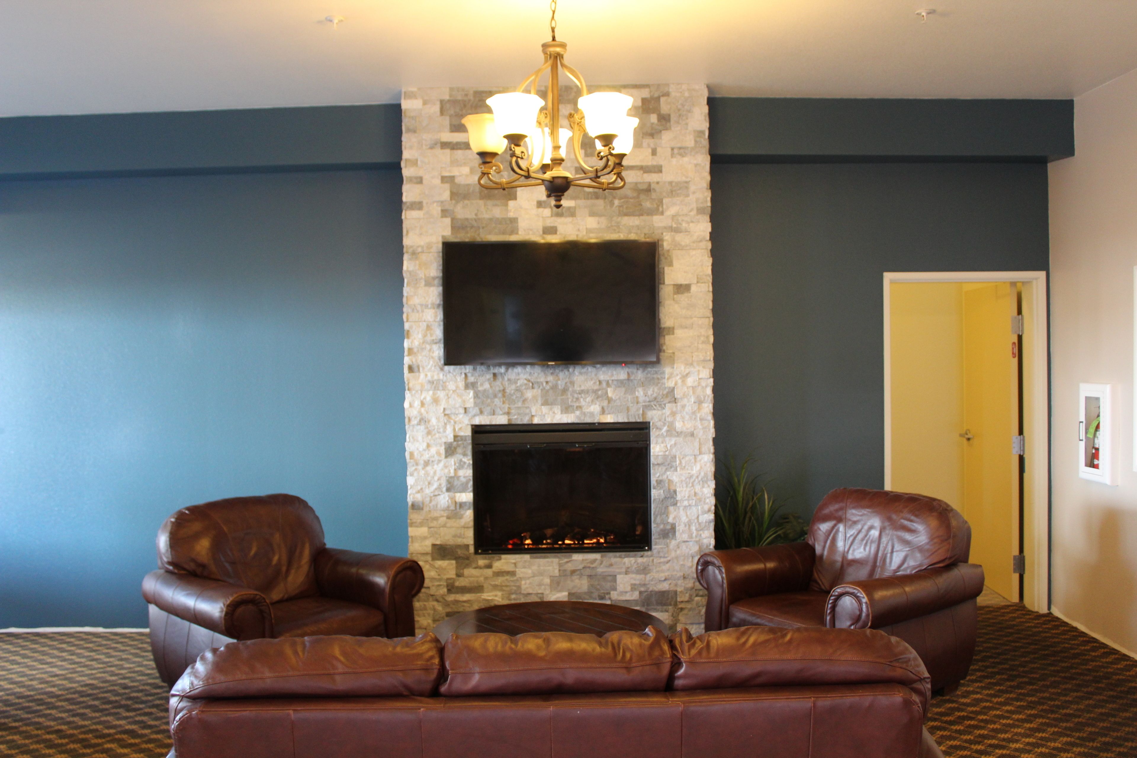A living room with a stone fireplace, leather sofas, and a flat-screen TV.