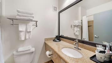 Un baño con lavamanos blanco, un espejo, toallero y un inodoro.